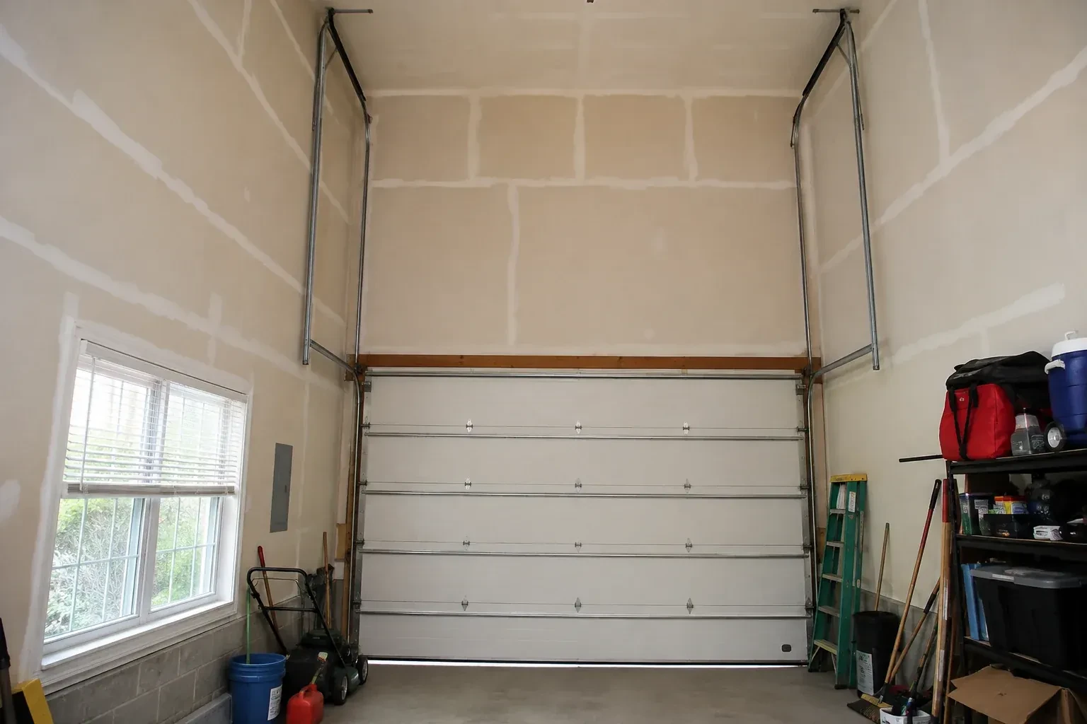 Tall garage interior with a sectional door and tracks extending into overhead space. — High-Lift Garage Door Conversion, Owen Sound